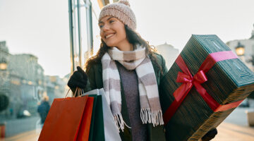 woman in winter clothes carrying christmas presents through mall for a blog about the best christmas shopping in bend