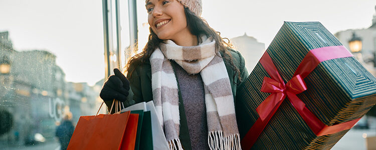 woman in winter clothes carrying christmas presents through mall for a blog about the best christmas shopping in bend